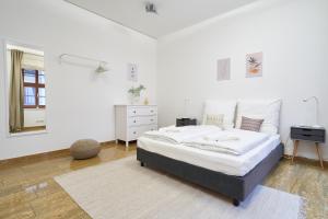 a white bedroom with a large bed and a mirror at Global Living - Design Apartments I City Center I Balcony I Smart-TV I Kitchen I Dresden in Dresden