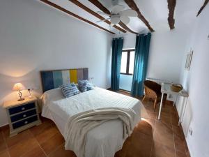 Dormitorio blanco con cama y mesa en La Rosita alojamiento rural, en Hinojares