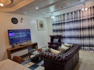 a living room with a leather couch and a television at Natako Apartments in Apenkwa