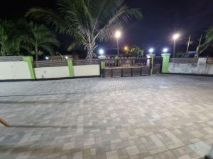 a parking lot with a fence and palm trees at night at Natako Apartments in Apenkwa