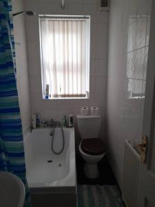 baño con aseo, bañera y ventana en Large house sleeps13 close to lfc stadium anfield, en Liverpool