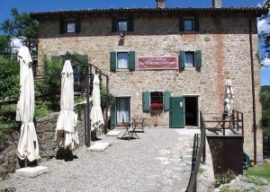 a building with closed umbrellas and chairs and a building at Locanda dei Fienili del Campiaro in Grizzana