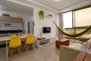 Il dispose d'une cuisine et d'un salon avec une table et des chaises jaunes. dans l'établissement Apto em Condomínio com Piscina de Borda Infinita P1320, à Florianópolis