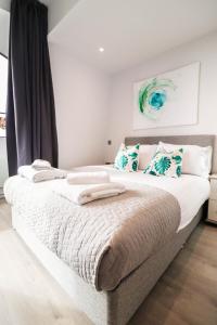 um quarto com uma cama grande e toalhas em BRAND NEW Apartments with FREE Parking and WIFI! em Staines