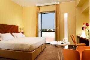 pokój hotelowy z łóżkiem, stołem i oknem w obiekcie UNAHOTELS Mediterraneo Milano w Mediolanie