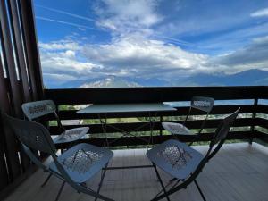 una mesa y sillas en un balcón con vistas en Cozy 2-bedroom appartment, lovely mountain escape en Crans-Montana