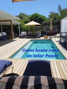 a swimming pool with a sign that reads guest house runs on solar power at Long Story Guest House in Plettenberg Bay