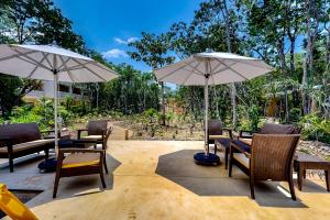 een patio met tafels, stoelen en parasols bij TAO Edena 95 in Tulum