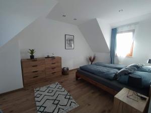 a bedroom with a bed and a dresser and a window at Klimatyczny Domek - całoroczny in Rydzewo