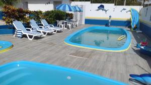 a pool with chairs and a table and an umbrella at Pousada Tio San in Japaratinga