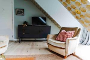 uma sala de estar com uma cadeira e uma televisão em L’écrin vintage - Hors Château & Marches de Bueren em Liège