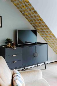 uma sala de estar com televisão em cima de uma cómoda em L’écrin vintage - Hors Château & Marches de Bueren em Liège