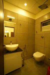 een badkamer met een wastafel, een toilet en een spiegel bij SREENARAYANA TOURIST HOME in Guruvāyūr