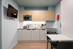 Coleman Court Summer Apartments في كورك: مطبخ مع دواليب بيضاء وطاولة مع كراسي
