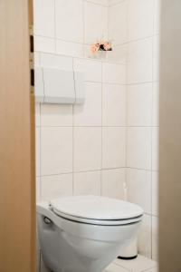 a white toilet in a white tiled bathroom at Landhaus Geisler in Tux