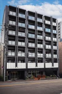 大阪市にあるPearl Spring116 hotelの通りに面した白いバルコニー付きのアパートメントビル