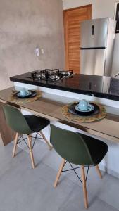 a kitchen with a counter with a stove and two chairs at Cobertura Vista Mar Carapibus - Cariri Praia - Apartamento completo com 02 quartos in Conde
