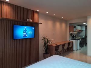 a room with a television on a wall with a kitchen at OITO ZERO UM - Flat Sol Victoria Marina in Salvador