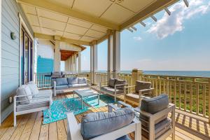 a porch with chairs and a table and the ocean at SBSL706 Luxury, Ocean front beach house, Hot Tub, Boardwalk to Beach in Port Aransas