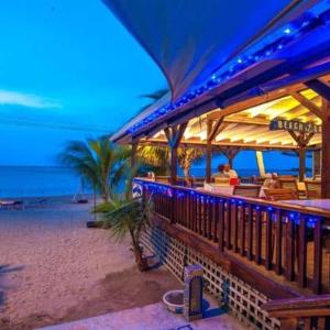 a restaurant on the beach at night with the ocean at Blue Bahia Resort in Sandy Bay