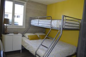 Chalet ALOHA في Saint-Côme-de-Fresné: غرفة نوم بسريرين بطابقين وجدار اصفر