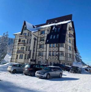 a large building with cars parked in the snow at Nivalis Residence 6 in Jahorina