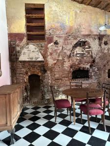 a room with a table and chairs and a brick wall at Hostel El Puesto in San Antonio de Areco
