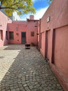 un edificio rosa con un banco delante en Hostel El Puesto en San Antonio de Areco