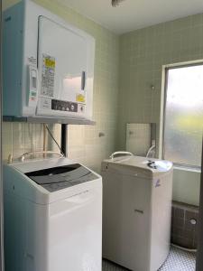 uma pequena cozinha com um lavatório e um micro-ondas em 北アルプス麓のゲストハウス林屋 203 em Ō-shinden