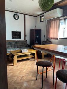 ein Wohnzimmer mit einem Sofa, einem Tisch und Stühlen in der Unterkunft 北アルプス麓のゲストハウス林屋 203 in Ō-shinden