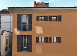 an orange building with black shuttered windows at Casa Brivio in Milan