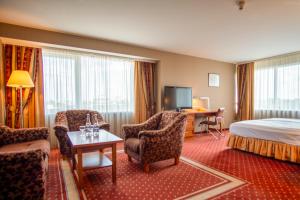 a hotel room with a bed and chairs and a television at VILNIUS PARK PLAZA HOTEL, Restaurant & Terrace, Panorama Bar, Conference & Banquet Center in Vilnius