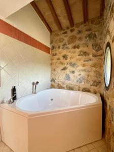 a bath tub in a bathroom with a stone wall at Podere Montale Il Borgo in Seggiano
