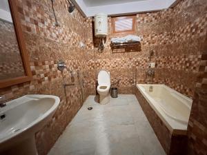 uma casa de banho com um lavatório, um WC e uma banheira em Bentenwood Resort - A Beutiful Scenic Mountain & River View em Manali