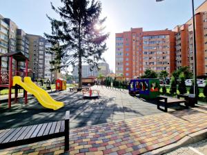 een park met een speeltuin met een glijbaan en banken bij Apartament on Chornovola, 40 ЖК "Варварівка" in Loetsk