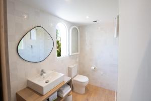 a bathroom with a sink and a toilet and a mirror at Hôtel Casa Marina in Saintes-Maries-de-la-Mer