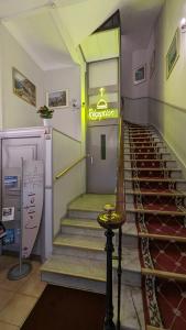 un escalier en colimaçon dans un bâtiment avec un panneau de néon dans l'établissement Hôtel Richelieu, à Menton
