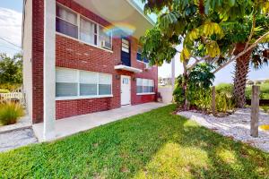 een rood bakstenen huis met een gazon ervoor bij Islander's Outpost in Dunedin