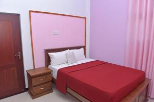 1 dormitorio con 1 cama con colcha roja en Sri Ra'anana Villa, en Marawila