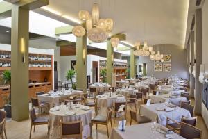 a restaurant with white tables and chairs and chandeliers at Hq La Galeria in Burgos