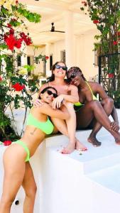 three women in bathing suits sitting on a ledge at Killi Luxury Villa in Moshi