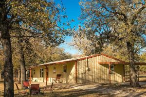 ein kleines gelbes Gebäude mit Bäumen davor in der Unterkunft Farm Cottage on homestead 20 min to Waco in Waco