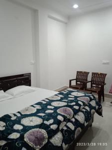a bedroom with a bed and two chairs at RADHA BNB ( HOMESTAY ) in Dharamshala