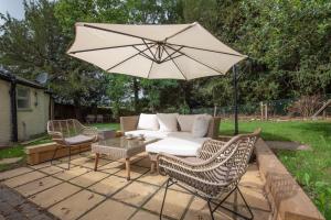 a patio with a couch and an umbrella and chairs at The Lodge in Rempstone