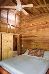 a bedroom with wooden walls and a ceiling fan at Jungle beach 2 bedroom cottage in Bocas Town