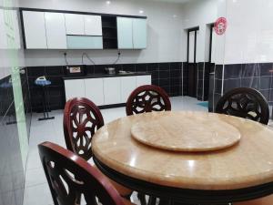 a kitchen with a wooden table and chairs at JMKT Homestay @ Bandar Seri Alam in Masai