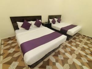 a bedroom with two beds with purple and white sheets at Hotel Star of Kurla - Nearest from Kurla - Near BKC in Mumbai