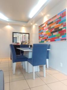 a dining room with blue chairs and a colorful wall at Apartamento Compartilhado Quarto 3 Oktoberfest in Blumenau