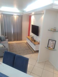 a living room with a couch and a television at Apartamento Compartilhado Quarto 3 Oktoberfest in Blumenau