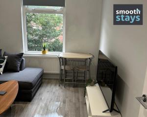 a living room with a couch and a table and a window at Modern 2 Bed Apartment By Smooth Stays Short Lets & Serviced Accommodation Preston With Parking Near Train Station in Preston